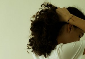 Woman with curly hair arranging her hair into a ponytail